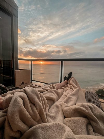 a person laying in a bed with a view of the ocean